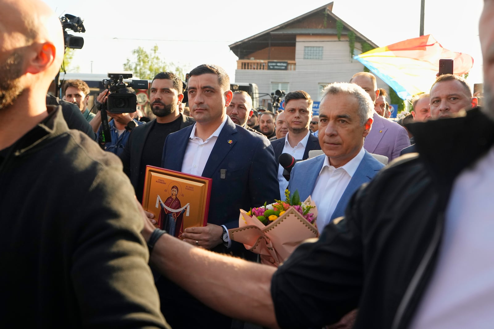 Presidential candidate George Simion, left, holds a religious icon as he walks with Calin Georgescu, winner of the first round of last year's annulled election, after they casted their votes in the first round of the presidential election redo in Bucharest, Romania, Sunday, May 4, 2025. (AP Photo/Vadim Ghirda)