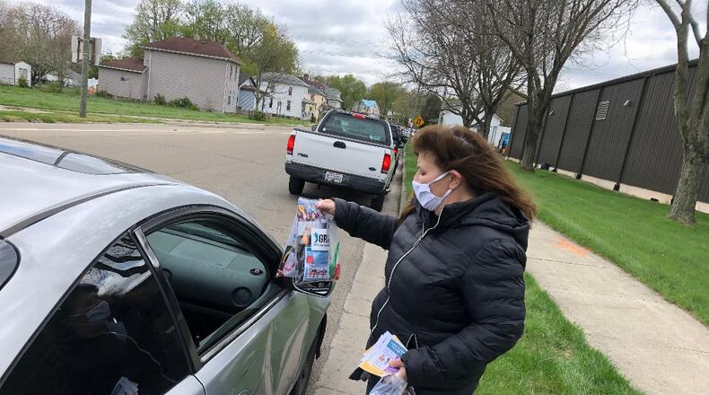 Trish Williams-Chase of the Clark County Substance Abuse Prevention Coalition's GROW Team hands out resource bags filled with a variety of items including a mask, candy, information and other items to people waiting to receive items from the Second Harvest Food Bank of Clark County on Friday afternoon. Photo by Brett Turner