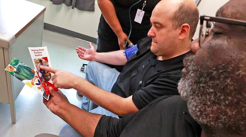 Vince Carter, health equity coordinator at the Clark County Combined Health District, gives Paden Frank some literature about Men's Health Month on Monday, June 26, 2023. BILL LACKEY/STAFF