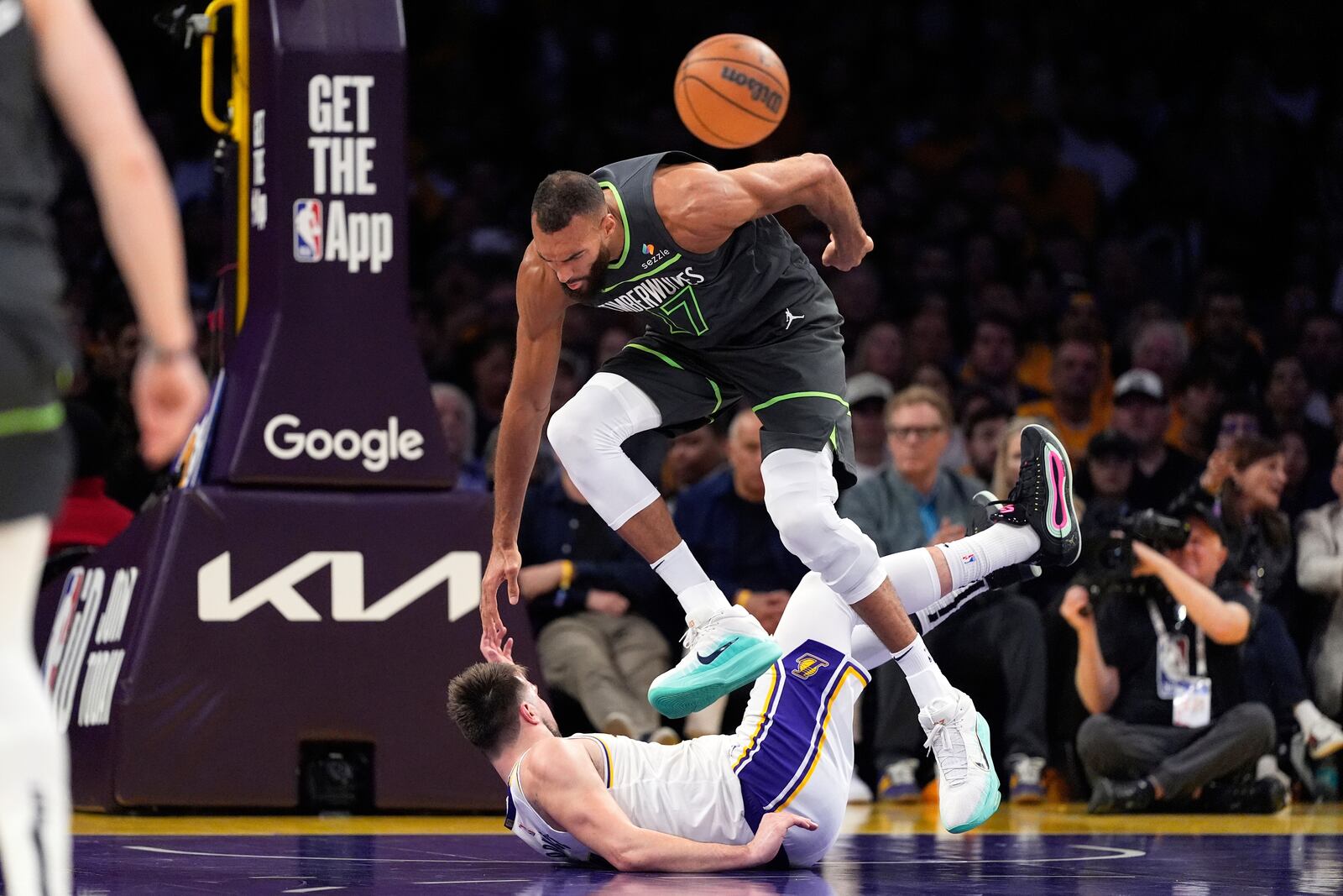 Minnesota Timberwolves center Rudy Gobert, top, trips over Los Angeles Lakers guard Luka Doncic during the first half in Game 1 of an NBA first-round playoff series Saturday, April 19, 2025, in Los Angeles. (AP Photo/Mark J. Terrill)