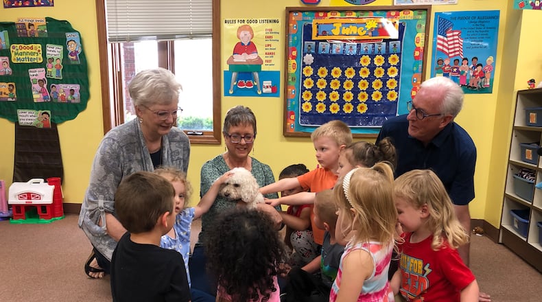Students of Maiden Lane Church of God's Christian EduCare program preschoolers gather around former director Margi Starr, left, current director Nikki Tackett and board member Greg Baker to pet the program mascot. EduCare is celebrating its 50th anniversary and seeking memories and stories of former students and family members for a celebration event in September.