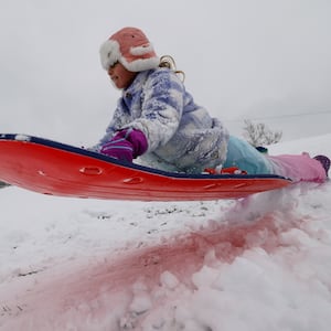 Luna Reed, 6, catches some air while sledding on a snow day off school Tuesday, Dec. 2, 2025 at St. John XXIII School in Middletown. NICK GRAHAM/STAFF