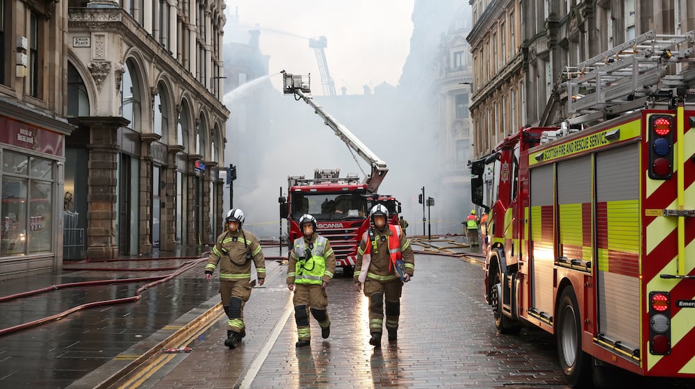 Firefighters damp down the remains of a fire which broke out in a building adjacent to Glasgow Central railway station on Sunday, in Glasgow, Scotland, Monday March 9, 2026. (Robert Perry/PA via AP)