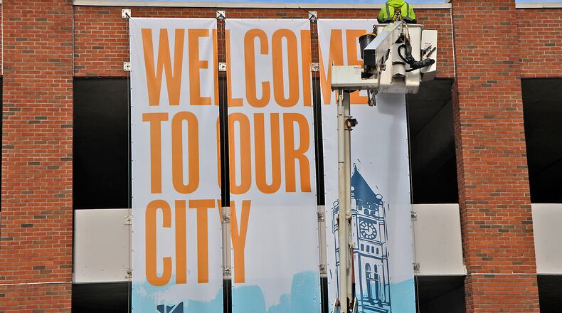 A City of Springfield service department employee uses a lift to hang a new banner on the Fountain Avenue side of the Park at the 99 parking garage Wednesday, April 3, 2024. BILL LACKEY/STAFF