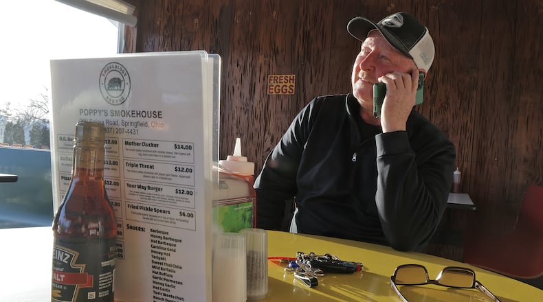 Steve Elliott, owner of Poppy's Smokehouse, answers a phone call asking if his new brick and mortar is open yet on Selma Road in Springfield. BILL LACKEY/STAFF