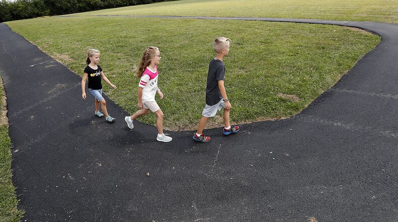 Micah, Mackenna and Jocelyn Sharbaugh walk around the new exercise track at New Carlisle Elementary Tuesday. Bill Lackey/Staff