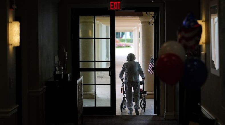 FILE - A woman uses a walker as she exits an assisted living building, July 4, 2025, in Boca Raton, Fla. (AP Photo/Rebecca Blackwell, File)