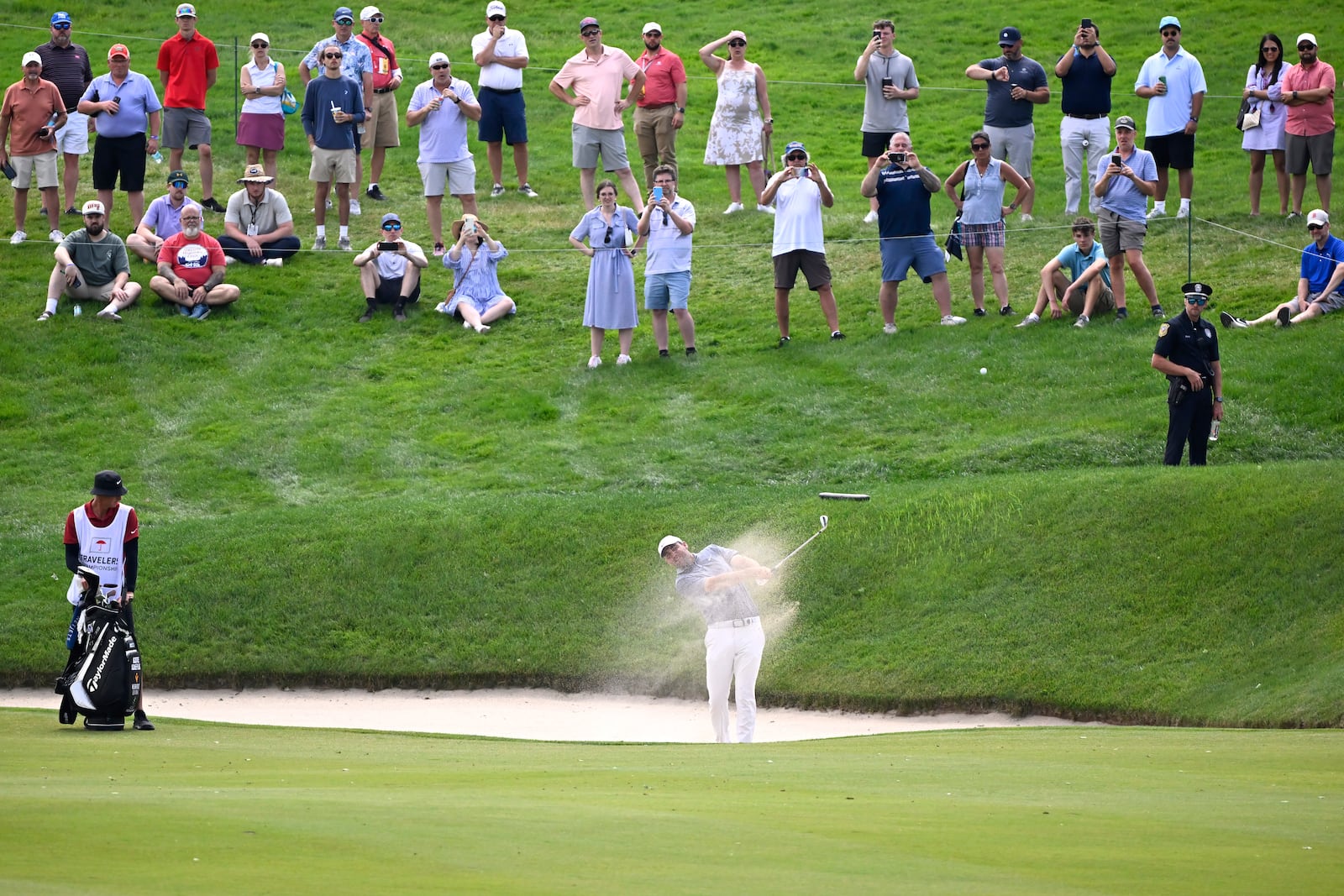 Scottie Scheffler, center, hits his second shot from the bunker to the water on the 17th hole during the second round of the Travelers Championship golf tournament at TPC River Highlands, Friday, June 20, 2025, in Cromwell, Conn. (AP Photo/Jessica Hill)