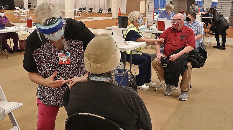 Clark County residents get their COVID vaccine shots at the Clark County Combined Health District's vaccine distribution center at the Upper Valley Mall on Feb. 23. BILL LACKEY/STAFF