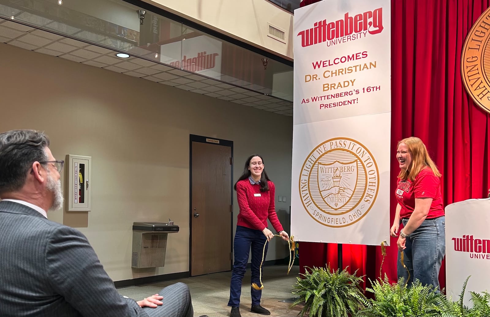 New Wittenberg University President Christian Brady (left) smiles as students unveil a sign announcing Brady's appointment on Friday, May 9, 2025 in Springfield. BROOKE SPURLOCK / STAFF