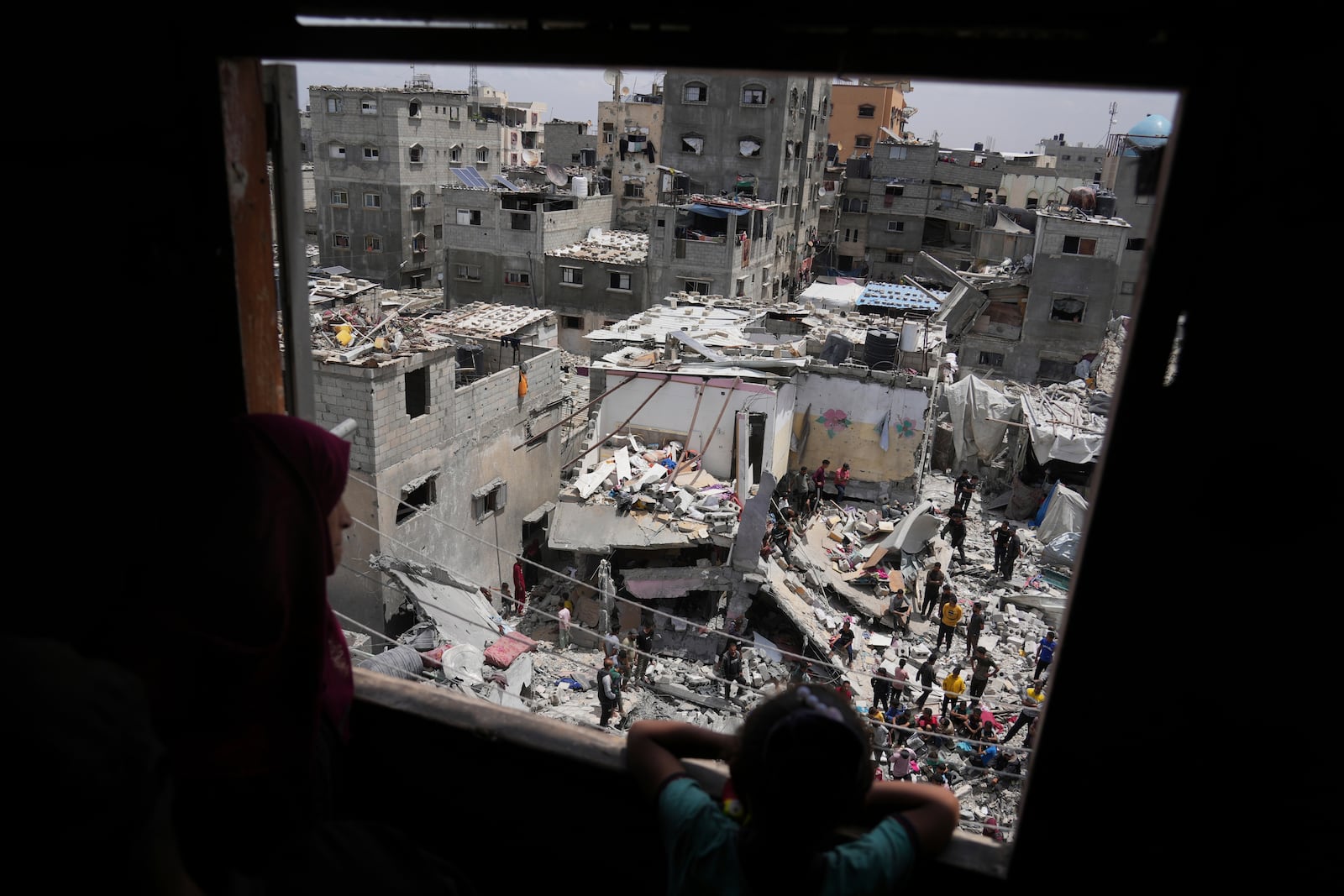 A child and a woman look as Palestinians search the rubble of a house targeted by an Israeli army strike that killed killing at least five members of the Abu Sahloul family in Khan Younis, in the southern Gaza Strip, Thursday, May 1, 2025. (AP Photo/Abdel Kareem Hana)