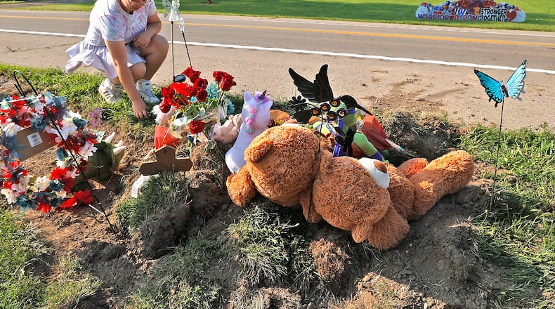 Madison Donnelly, a Northwestern Schools alumnus, places flowers Wednesday, August 23, 2023 at a memorial along Troy Road at the site of Tuesday's fatal bus crash. BILL LACKEY/STAFF