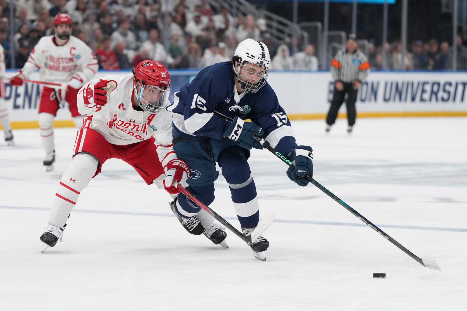 Penn State's Charlie Cerrato (15) handles the puck as Boston University's Quinn Hutson defends during the first period in a semifinal game in the NCAA Frozen Four men's college hockey tournament, Thursday, April 10, 2025, in St. Louis (AP Photo/Jeff Roberson)