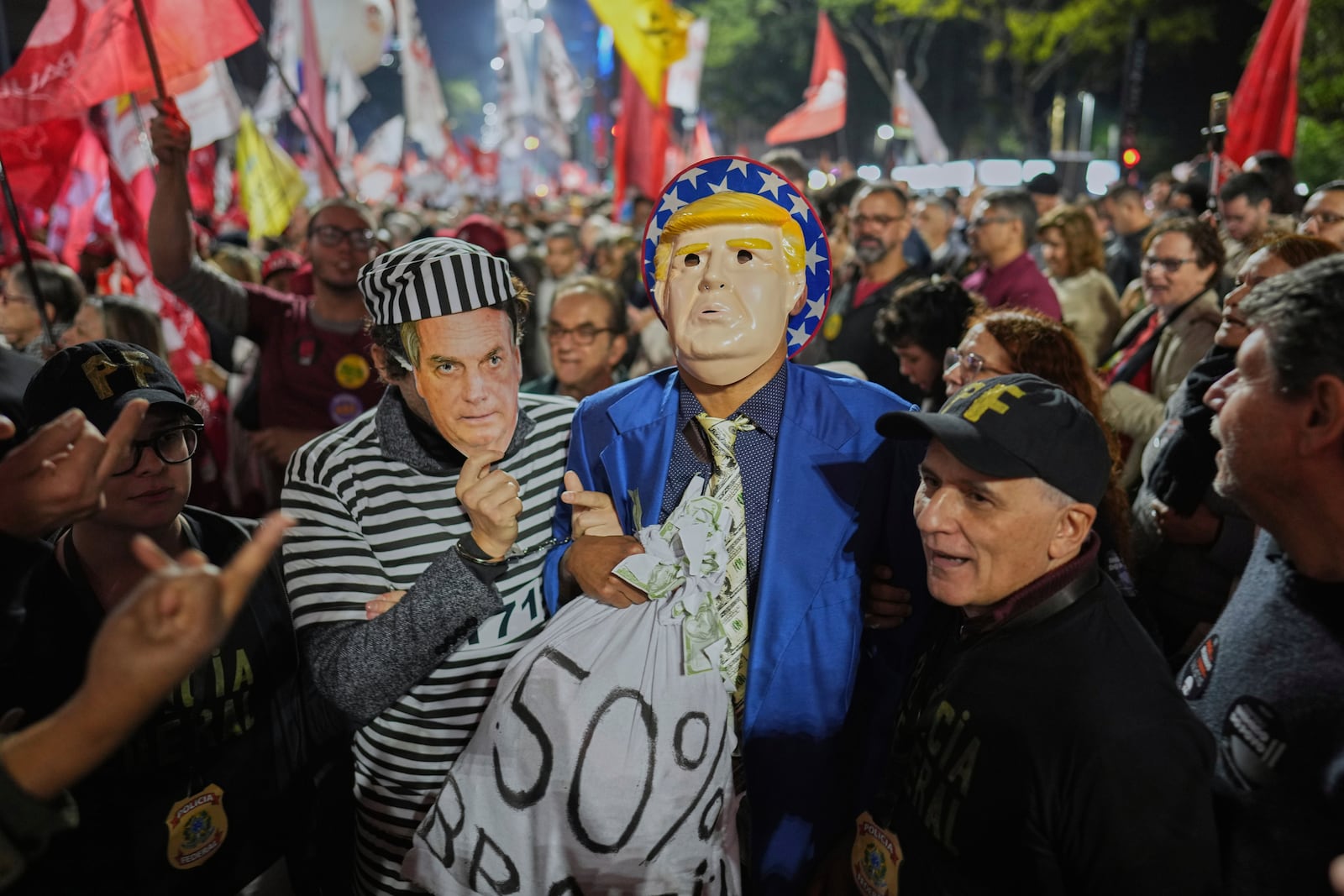 Supporters of Brazilian President Luiz Inacio Lula da Silva, wearing masks of U.S. President Donald Trump and former President Jair Bolsonaro as a prisoner, protest Trump's announcement of 50% tariffs on Brazil, in São Paulo, Thursday, July 10, 2025. (AP Photo/Andre Penner)