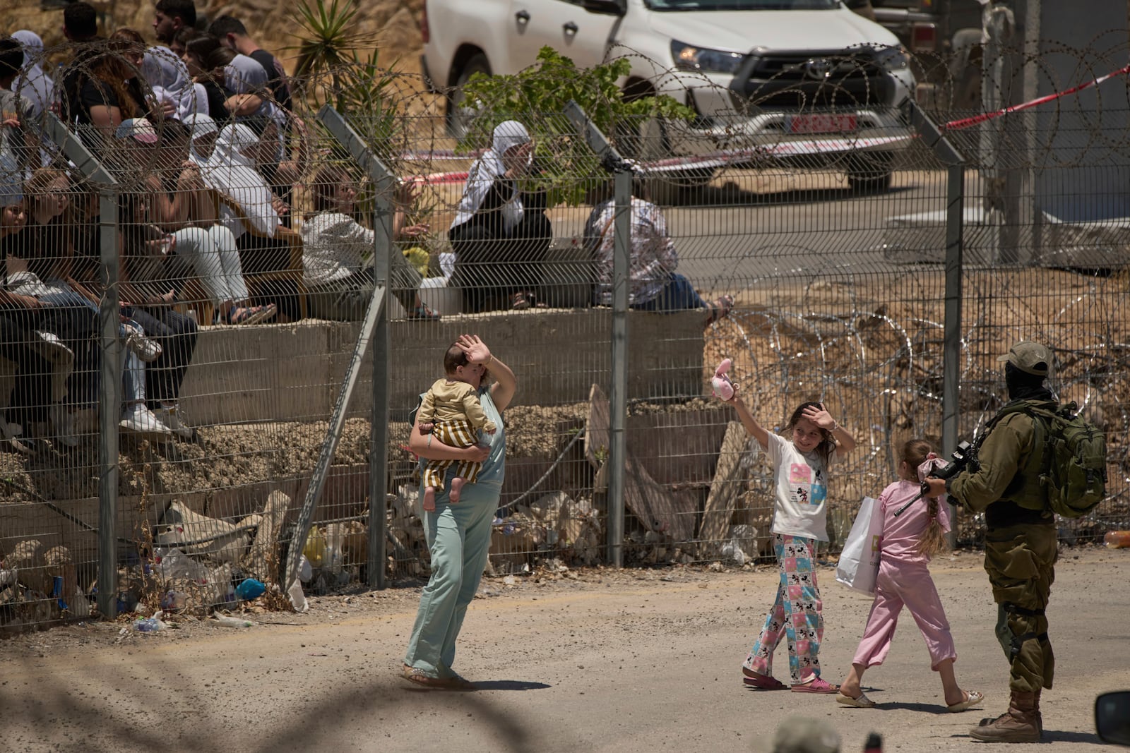 Members of a Syrian Druze family wave goodbye as they cross back into Syria at the Israeli-Syrian border, in the Israeli-controlled Golan Heights town of Majdal Shams, Thursday, July 17, 2025. (AP Photo/Leo Correa)