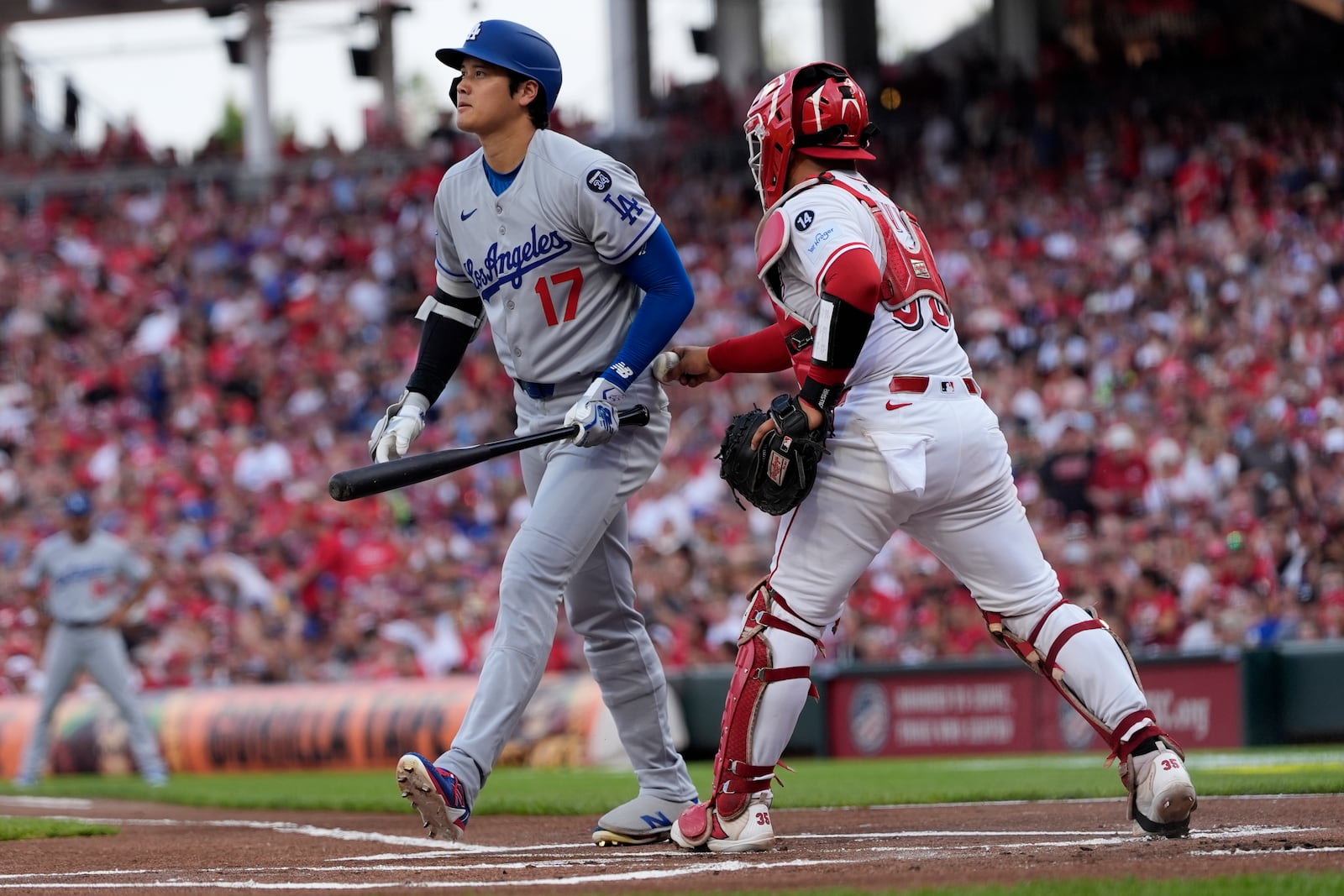 Los Angeles Dodgers' Shohei Ohtani, left, turns to walk to the dugout as Cincinnati Reds catcher Jose Trevino tags Othani out after dropping the third strike during the first inning of a baseball game, Tuesday, July 29, 2025, in Cincinnati. (AP Photo/Carolyn Kaster)