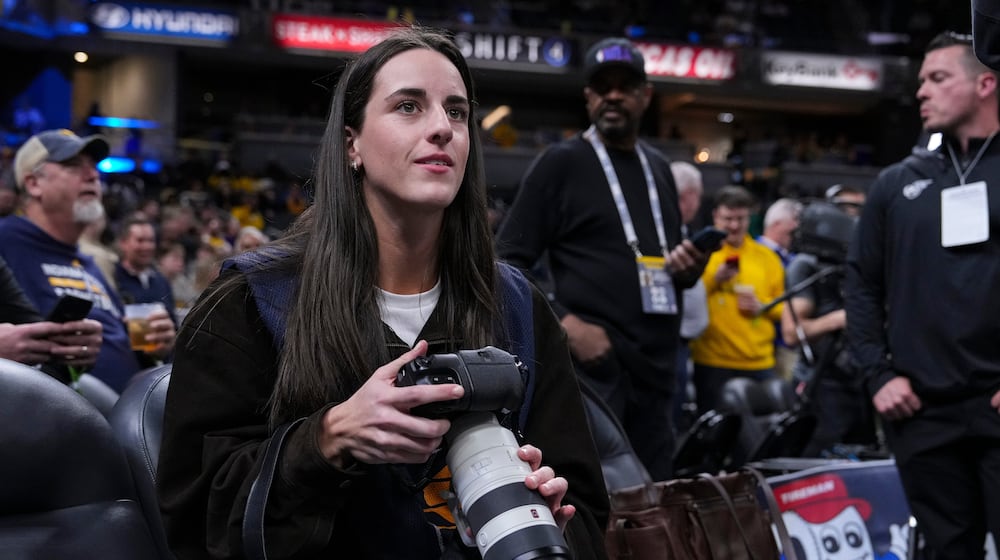 Indiana Fever guard Caitlyn Clark takes photos during pregame before an NBA basketball game between the Indiana Pacers and the Los Angeles Lakers in Indianapolis, Wednesday, March 25, 2026. (AP Photo/Michael Conroy)