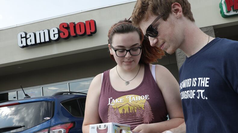 Casey McGraw and Tucker Goldberg look over the items they purchased at Game Stop on Bechtle Avenue Friday as they leave the store. A manager at the store says it is expected to remain open, after company leaders announced they would close up to 200 locations. Plans for a second Springfield location were unclear Friday. BILL LACKEY/STAFF