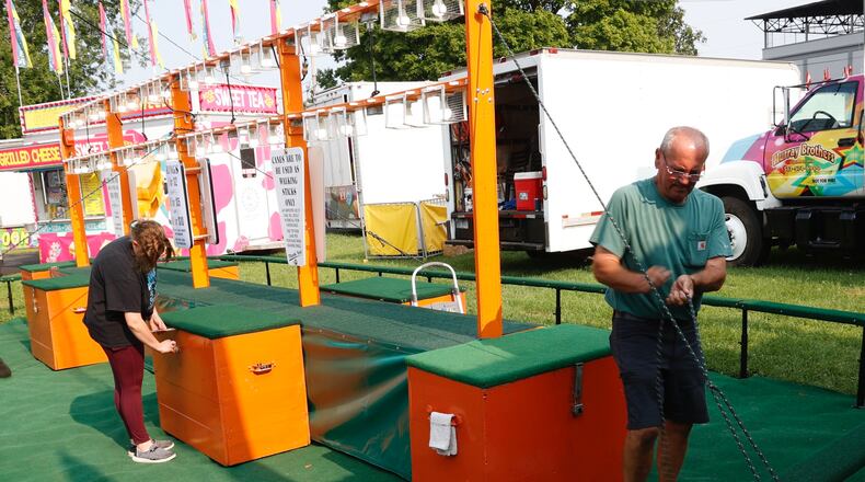 Karl Dearwester, right, and his crew were busy Wednesday, August 2, 2023 setting up possibly the oldest carnival game in Ohio. Dearwester Canes has been at the Champaign County Fair, in the same spot since 1892. BILL LACKEY/STAFF
