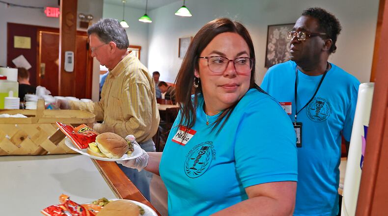 Marcie Reynolds, from the Clark County Municipal Drug Court, takes two meals to hungry people at the Springfield Soup Kitchen Monday, May 22, 2023 as she and other members of the Drug Court volunteered at the Soup Kitchen. BILL LACKEY/STAFF