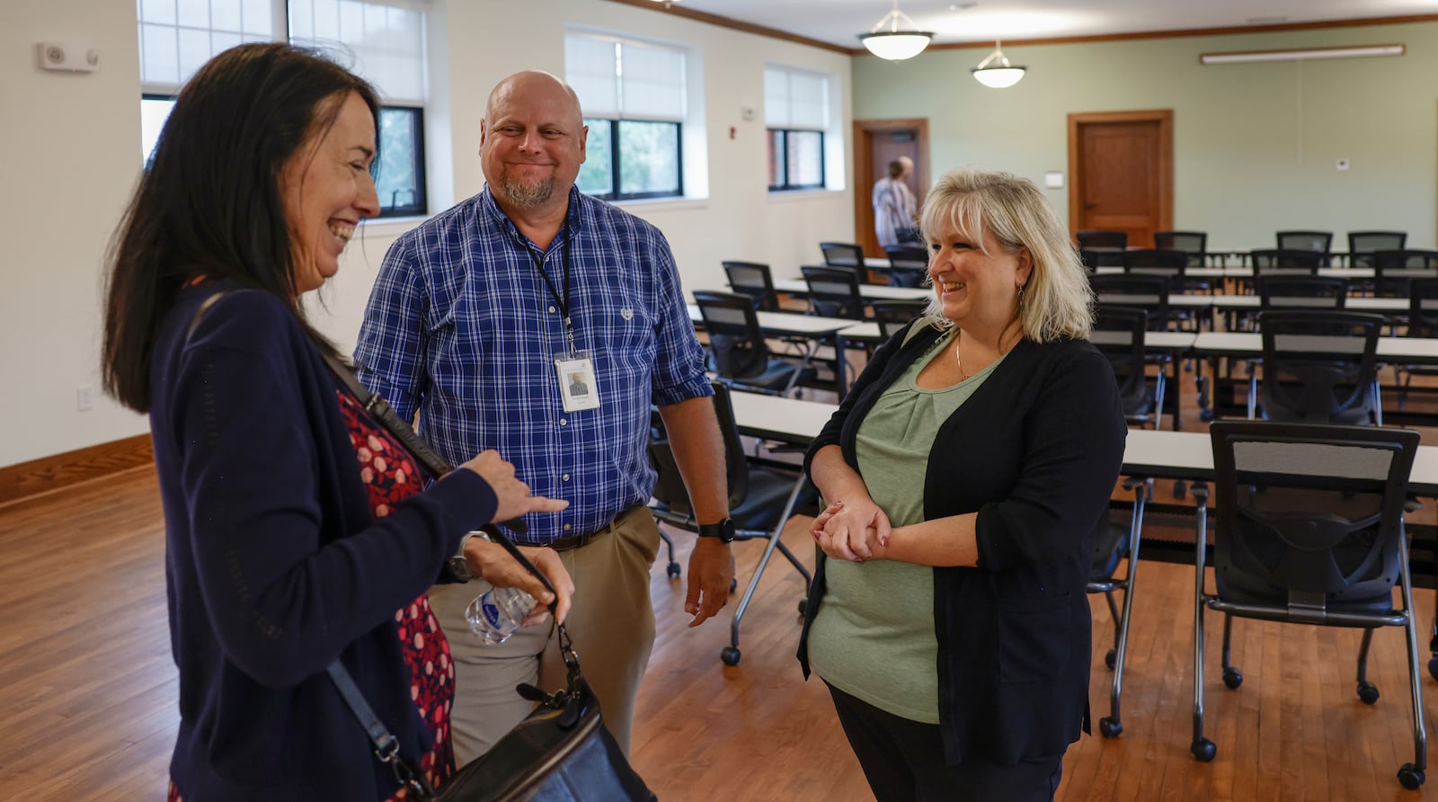 Michelle Noble, left, Clark County assistant administrator & HR director, Thomas McGrath, center, Clark County Department of Job & Family Services director, and Sharon DeVore, Ride Plus Program supervisor, share laughs during the grand reopening of the $4.6M renovation project of the Home Road campus of the Clark County Department of Job and Family Services on Wednesday, August 20, 2025, in Springfield. JOSEPH COOKE/STAFF
