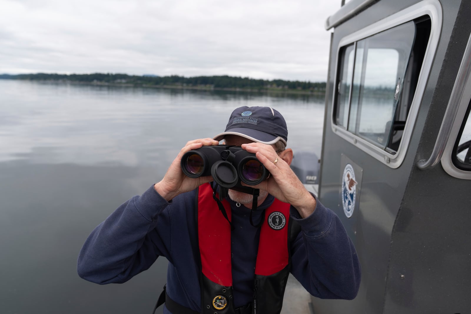 Washington Department of Natural Resources' Lowell Dickson watches as a helicopter moves an abandoned ship on Wednesday, June 4, 2025, in Olympia, Wash. (AP Photo/Jenny Kane)