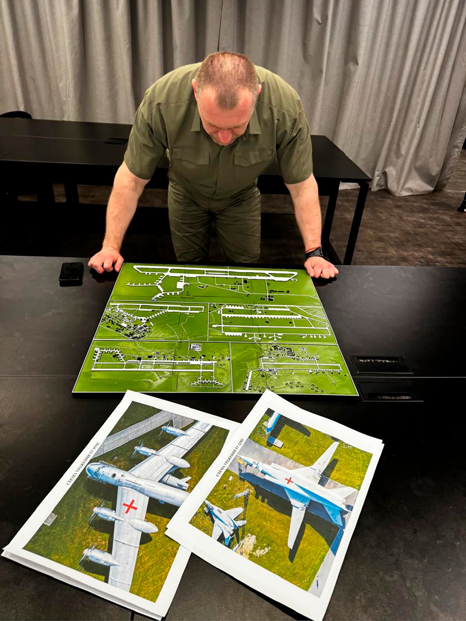 In this undated photo provided by the Ukrainian Security Service, head of the Security Service Vasyl Malyuk studies a photo of a map of Russia's strategic aviation location in his office in Ukraine. (Ukrainian Security Service via AP)