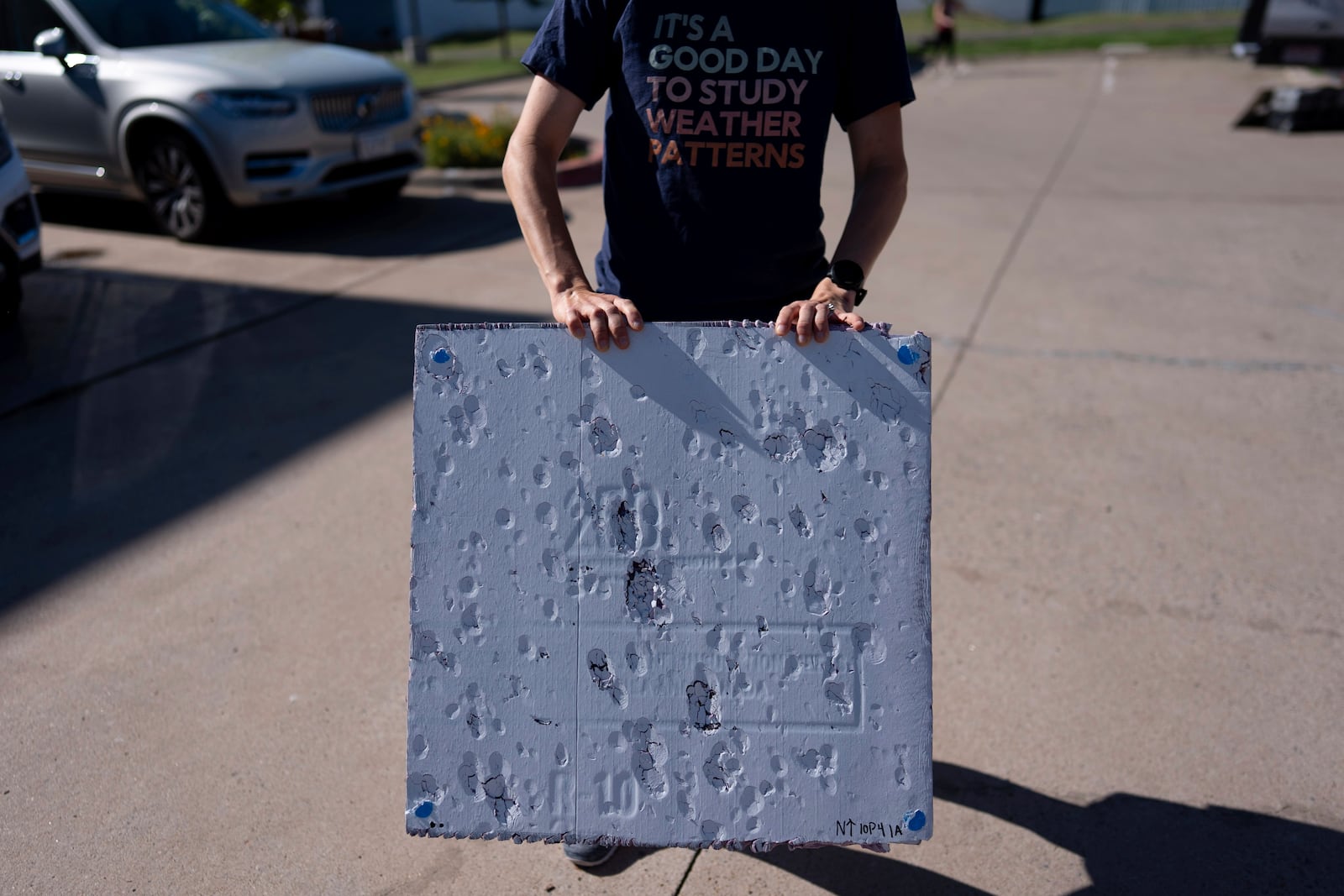 Hannah Vagasky holds a foam board hail pad covered with impact dents in a parking lot Tuesday, June 3, 2025, in Shamrock, Texas, as the team prepares for a day of hailstorm chasing. The hail pad is used to measure the size, angle of impact and intensity of hail. (AP Photo/Carolyn Kaster)