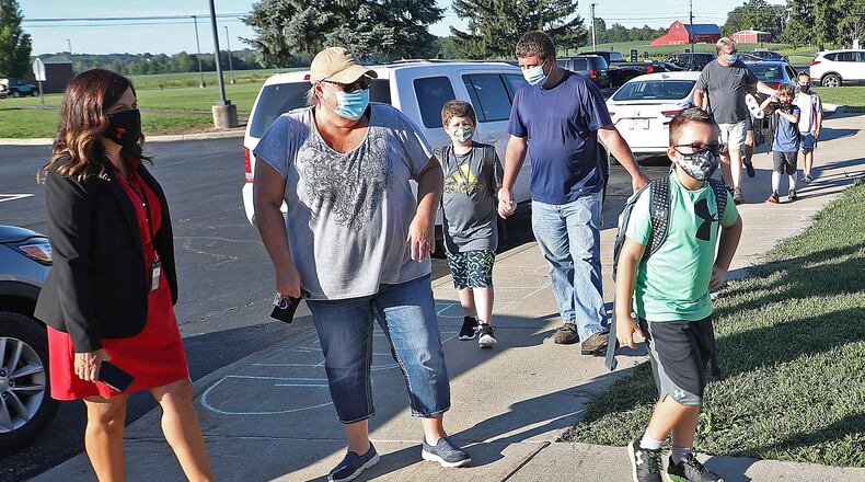 Triad Superintendent Vickie Hoffman, left, greets students and their families as they arrive for the first day of school on Thursday. Champaign County remains at a level 2, keeping district reopening plans the same. Clark County has upgraded to a level 3, but districts are also keeping their reopening plans the same as well. BILL LACKEY/STAFF