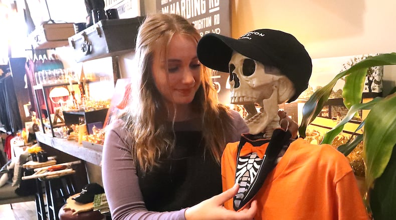 Mallory Janicki fixes a bow tie on a skeleton decoration at Champion City Guide and Supply Friday, Oct. 21, 2022 in downtown Springfield. BILL LACKEY/STAFF