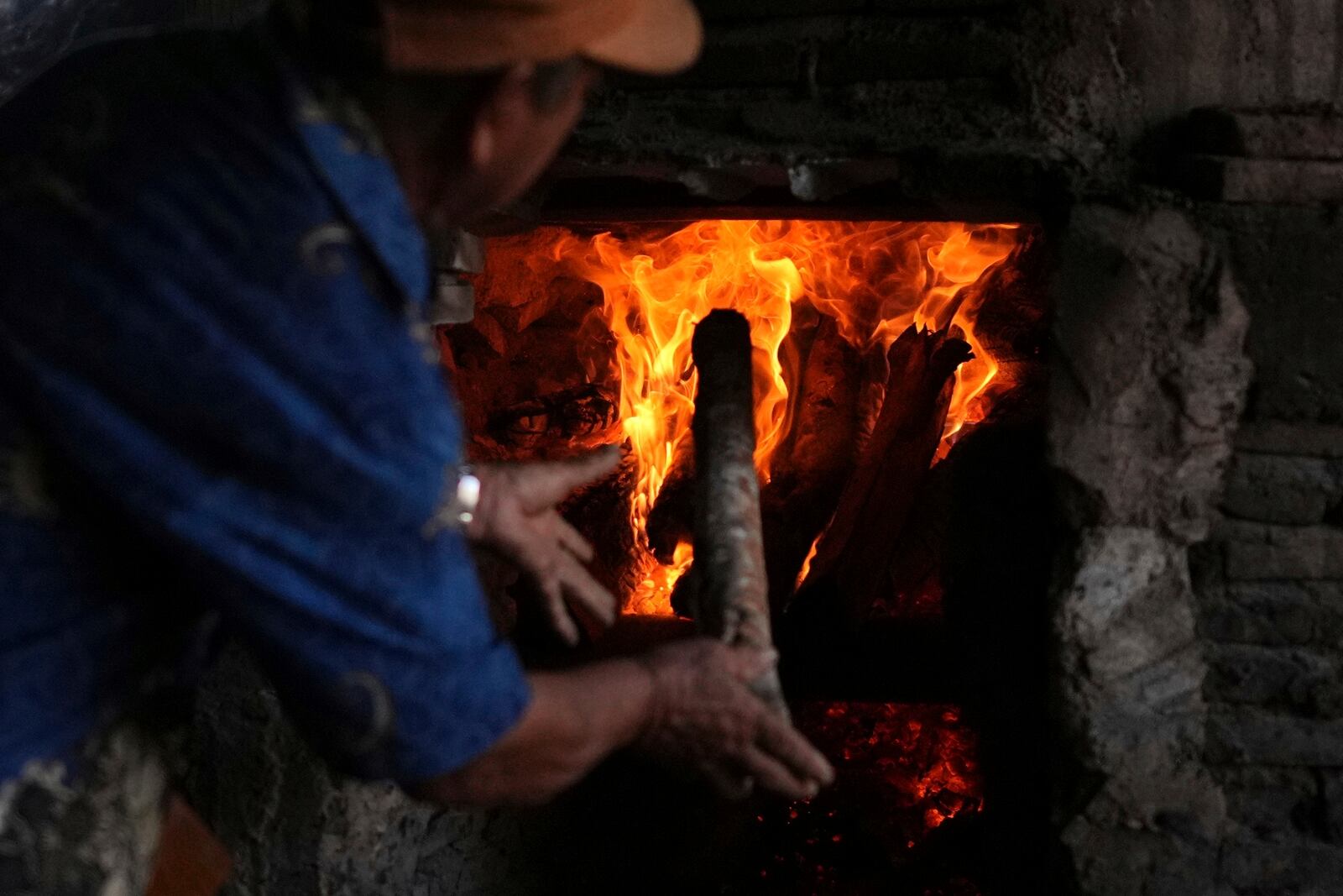 A farmer throws firewood into a furnace at a patchouli refinery in Simboro, West Sulawesi, Indonesia, Wednesday, Feb. 26, 2025. (AP Photo/Dita Alangkara)