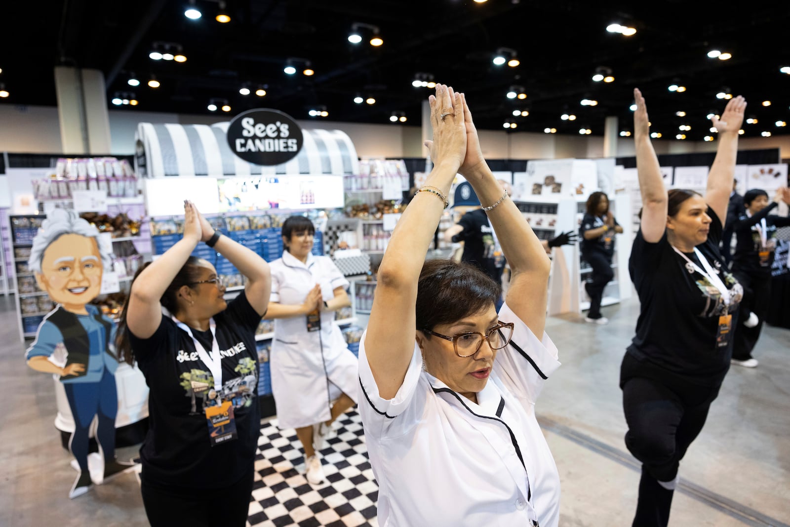 Marcy Gomez of Pasadena, Cal., does yoga with fellow Sees Candies employees before doors open to shareholders at CHI Health Center Omaha for the Berkshire Hathaway annual meeting Saturday, May 3, 2025, in Omaha, Neb. (AP Photo/Rebecca S. Gratz)