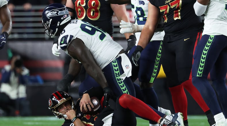 San Francisco 49ers quarterback Brock Purdy, bottom, reacts after being sacked by Seattle Seahawks defensive tackle Jarran Reed, middle, during the second half of an NFL football game in Santa Clara, Calif., Saturday, Jan. 3, 2026. (AP Photo/Jed Jacobsohn)