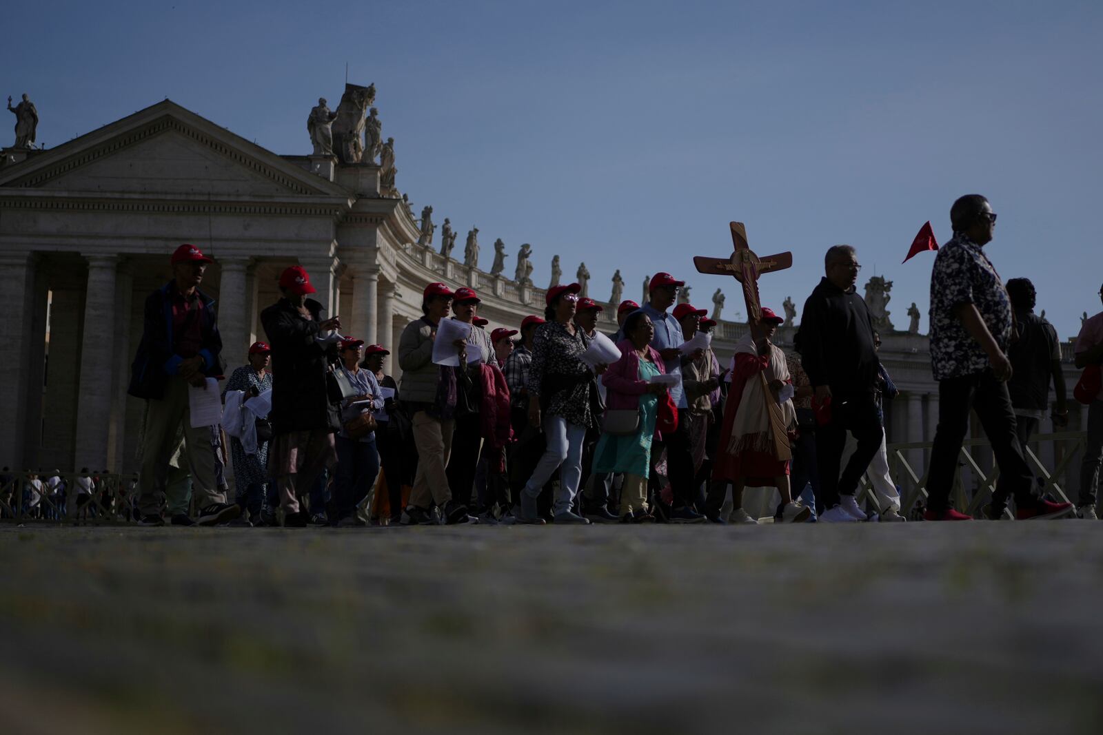 Pilgrims carrying a cross make their way to the Holy Door in St. Peter's Square at the Vatican after Cardinal Camerlengo Kevin Joseph Farrell announced the death of Pope Francis, Monday, April 21, 2025. (AP Photo/Alessandra Tarantino)