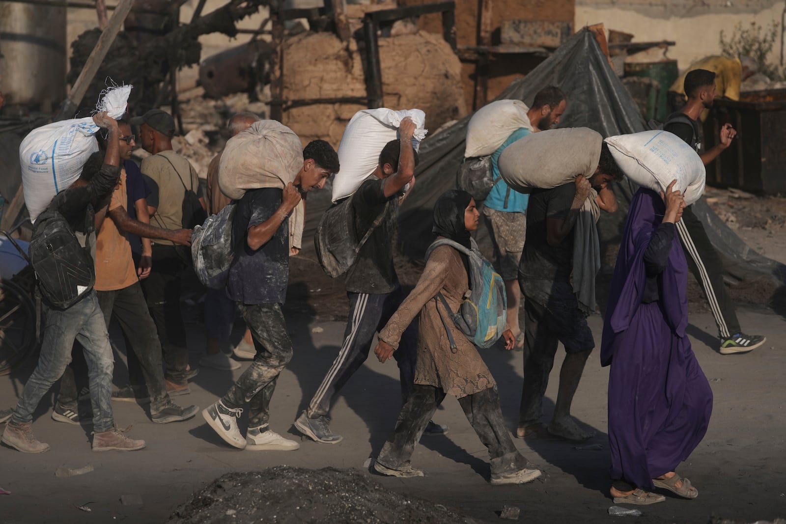 Palestinians carry sacks of flour unloaded from a humanitarian aid convoy that reached Gaza City from the northern Gaza Strip, Saturday, July 26, 2025. (AP Photo/Jehad Alshrafi)