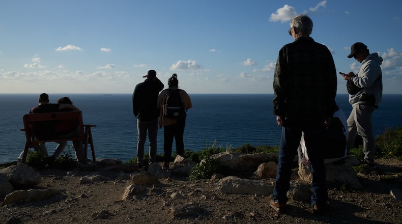 People gather at a lookout to look for the possible arrival of the US Navy's aircraft carrier USS Gerald R. Ford in the Mediterranean Sea near the coast of Haifa, northern Israel, Friday, Feb. 27, 2026. (AP Photo/Leo Correa)