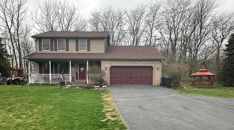 The front of home has an asphalt driveway that leads to a two-car attached garage. The house has a covered front porch with railings. CONTRIBUTED PHOTOS