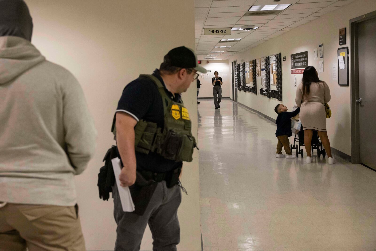 A border patrol agent looks at a family outside an immigration courtroom at the Jacob K. Javits Federal Building in New York, Tuesday, June 10, 2025. (AP Photo/Yuki Iwamura)
