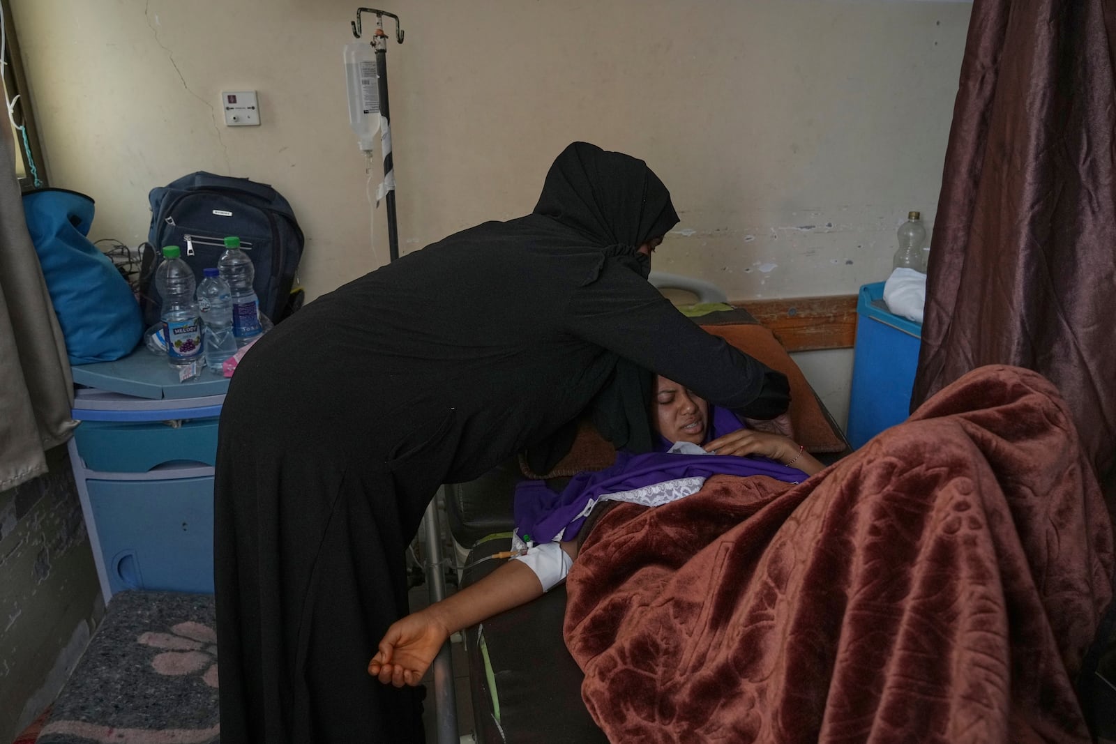 Salwa Faraj cares for her sister, Asmaa Faraj, who was injured in an Israeli army strike, at Nasser Hospital in Khan Younis, Gaza Strip, Tuesday, May 6, 2025. (AP Photo/Abdel Kareem Hana)