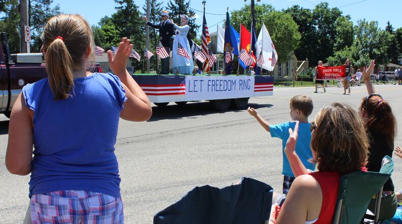 Parade watchers wave to the Let Freedom Ring float as it moves thru downtown Enon during the annual July 4th parade. The parade is sponsored by Mad River Twp Fire and EMS department. Jeff Guerini/Staff