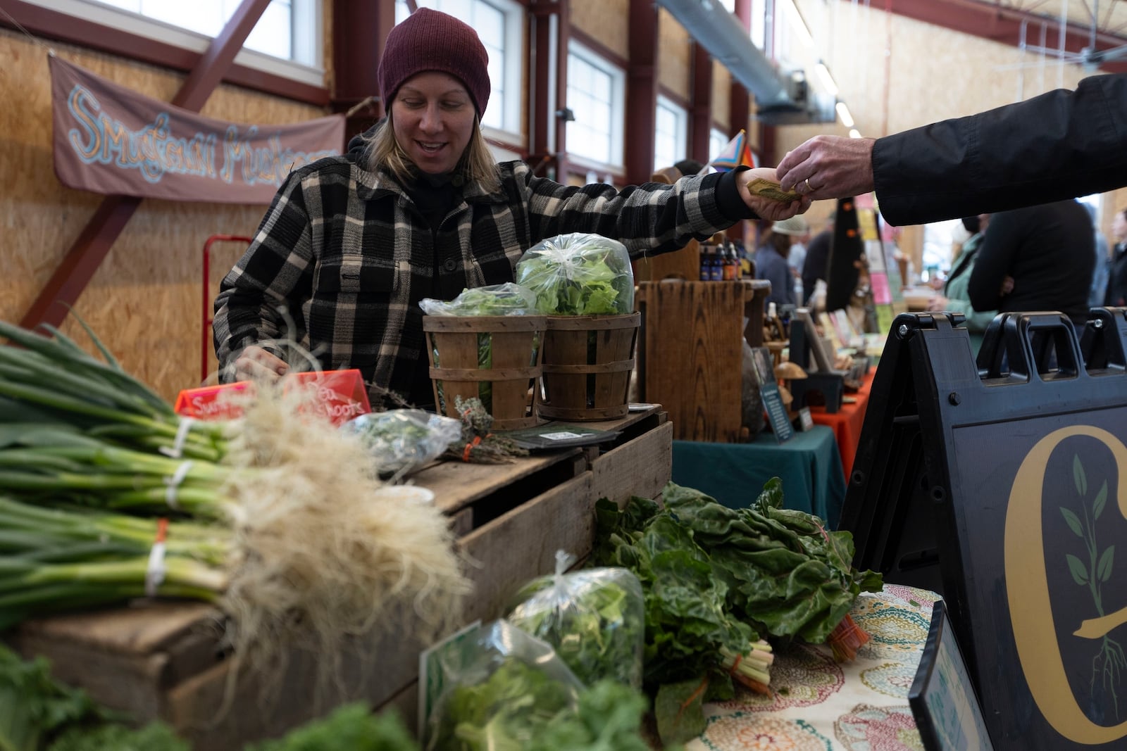 Courtney Klee, an employee of Growing Family Farms, handles a purchase at the Brighton Farmers Market on Sunday, March 23, 2025, in Brighton, N.Y. (Caitlyn Daproza via AP)