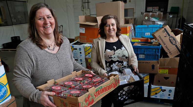 Two recent hires at the Second Harvest Food Bank, Toni Tayloe-Haddix, left, and Jennifer Brunner, help out during a food distribution Friday, March 17, 2023. BILL LACKEY/STAFF