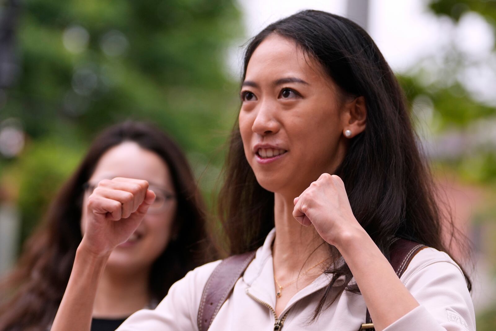 Yurong "Luanna" Jiang, who delivered a speech at her Harvard University commencement, raises her fists while talking with friends, Friday, May 30, 2025, in Cambridge, Mass. (AP Photo/Charles Krupa)