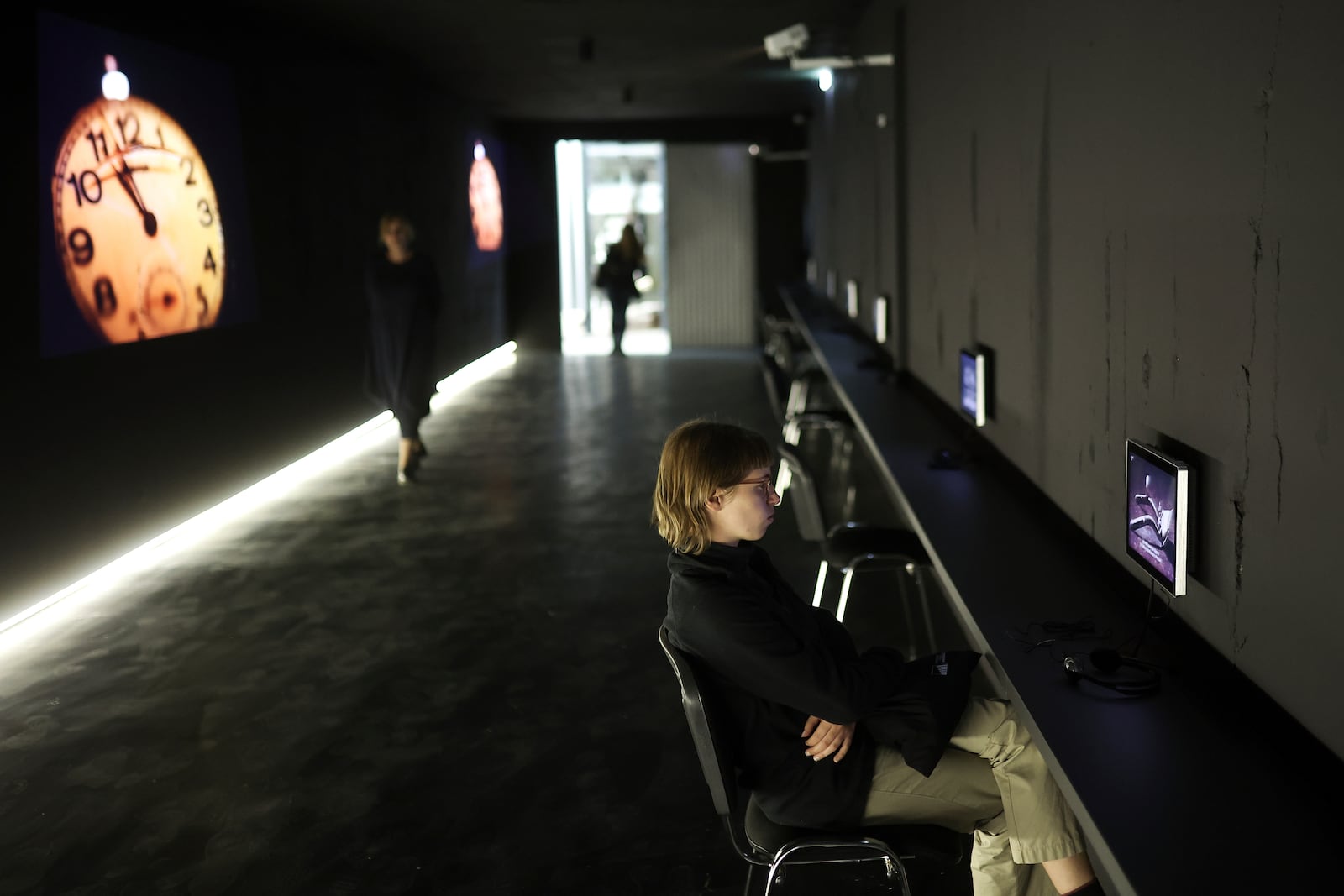 Woman watches a video, part of the exhibition "Lives Beyond the Fields of Death" opened at the Srebrenica Memorial Center in Potocari, Bosnia, Thursday, July 10, 2025. (AP Photo/Armin Durgut)