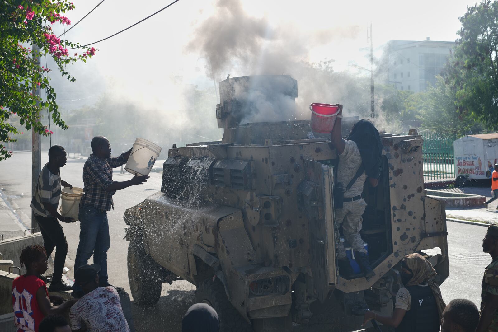 Police and civilians attempt to put out a fire set by gang members on an armored police vehicle in a gang-controlled area of ​​Port-au-Prince, Haiti, Monday, Jan. 19, 2026. (AP Photo/Odelyn Joseph)