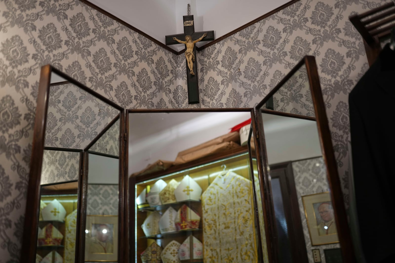 A crucifix hangs over a mirror reflecting ecclesiastic clothes inside the dressing room at the Gammarelli tailor shop in Rome, Wednesday, April 30, 2025. (AP Photo/Francisco Seco)