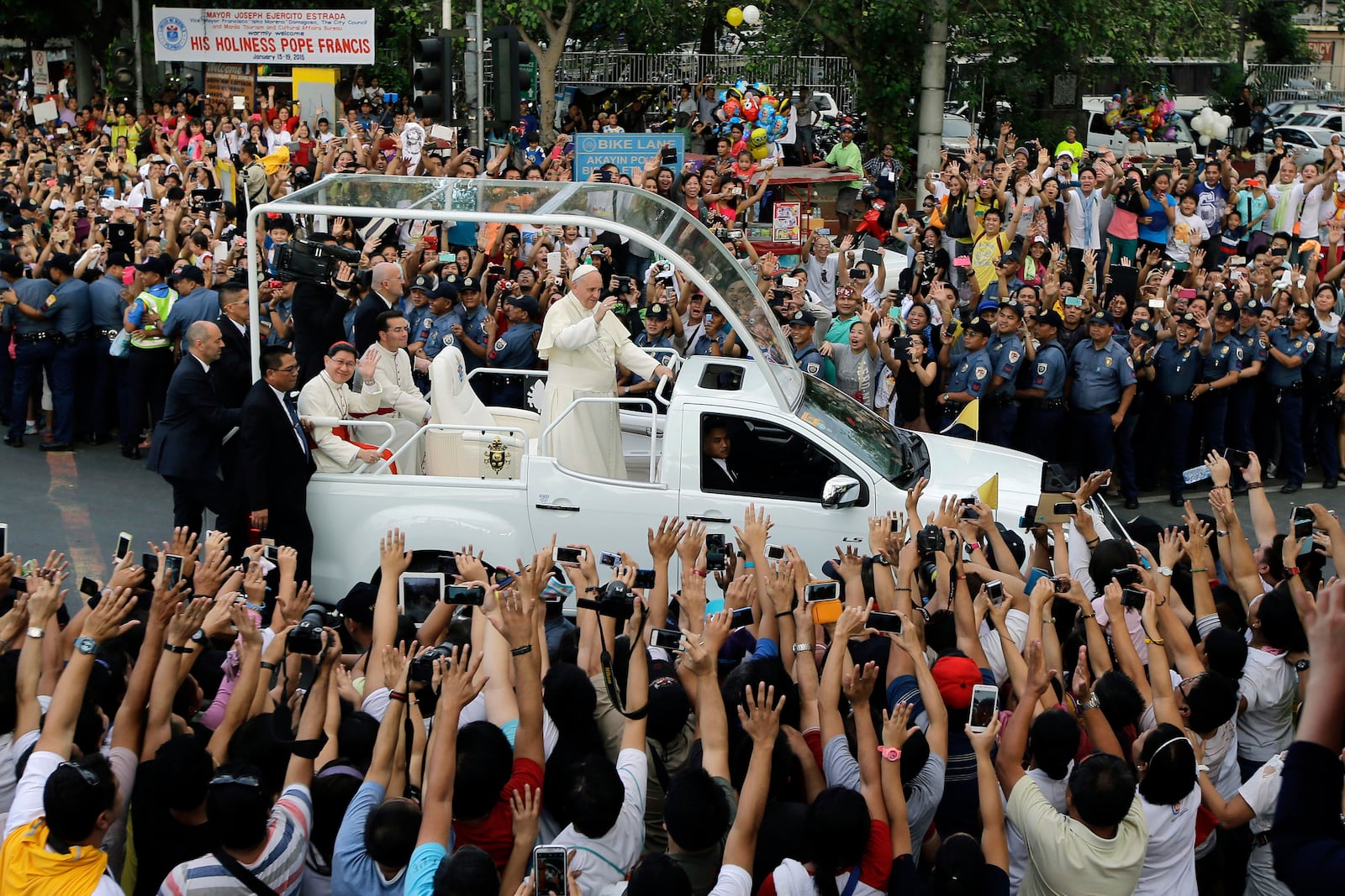 FILE - Pope Francis waves to onlookers from his popemobile as his motorcade passes by on the way to another "Meeting With Families" at the Mall of Asia Arena in Manila, Philippines, Jan. 16, 2015. (AP Photo/Bullit Marquez, File)