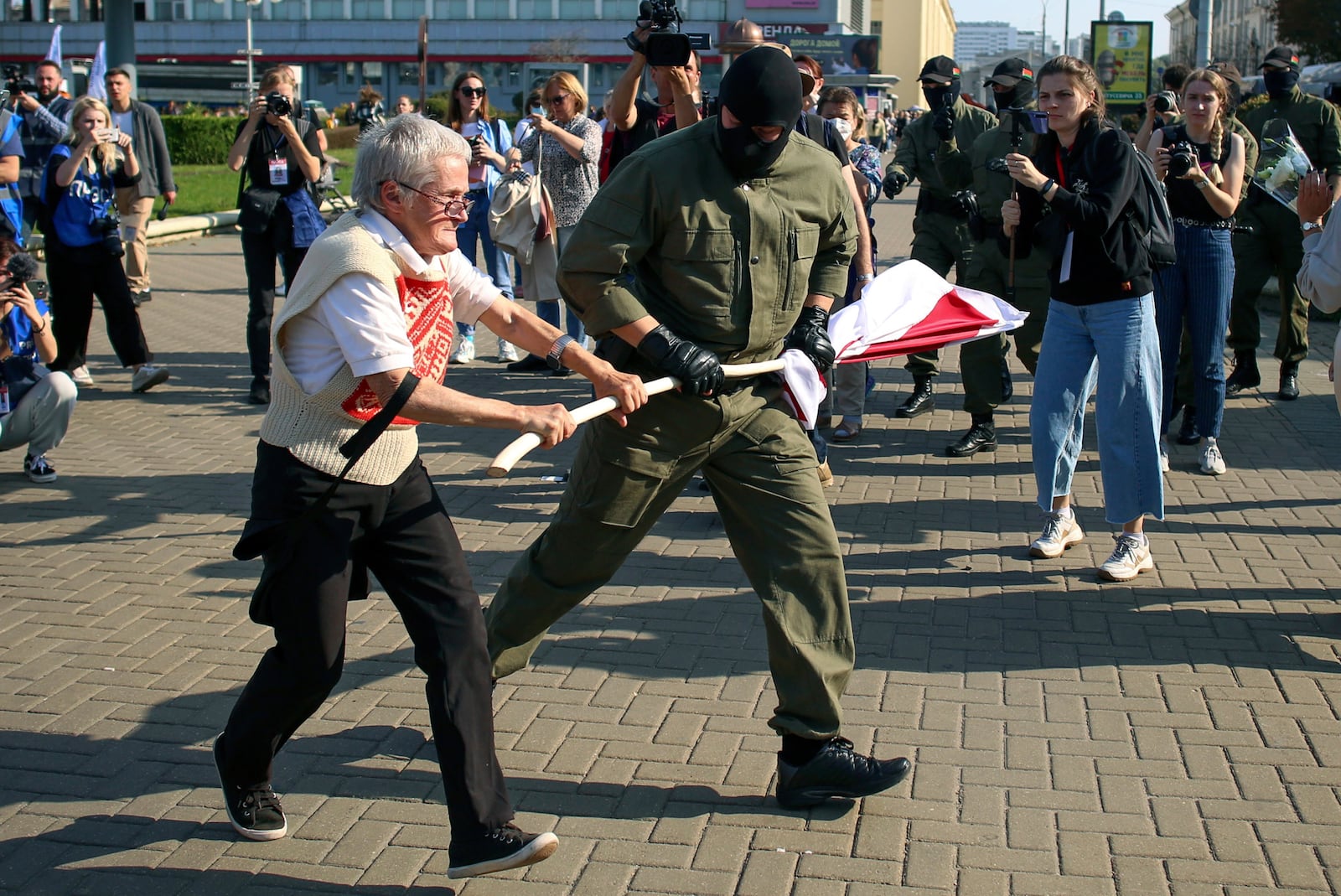FILE - A police officer tries to take away an old Belarusian national flag from Nina Bahinskaya's, 73, hands during an opposition rally to protest the official presidential election results in Minsk, Belarus, Saturday, Sept. 26, 2020. (AP Photo/TUT.by, File)