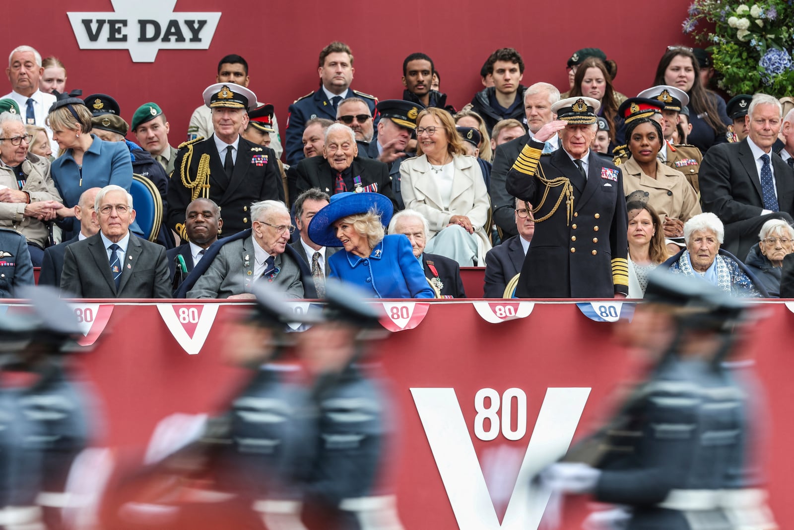 Britain's King Charles III salutes next to Queen Camilla during the military procession marking the 80th anniversary of VE Day, in London, Monday, May 5, 2025. (Toby Melville/Pool Photo via AP)