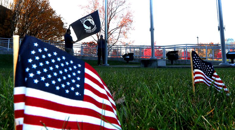 A POW-MIA flag joins several hundred small American flags as Clark State College employees Ryan Green and Brian Guthrie replace the Clark State flag in front of the Sara T. Landess Technology and Learning Center for Veteran's Day last year. BILL LACKEY/STAFF
